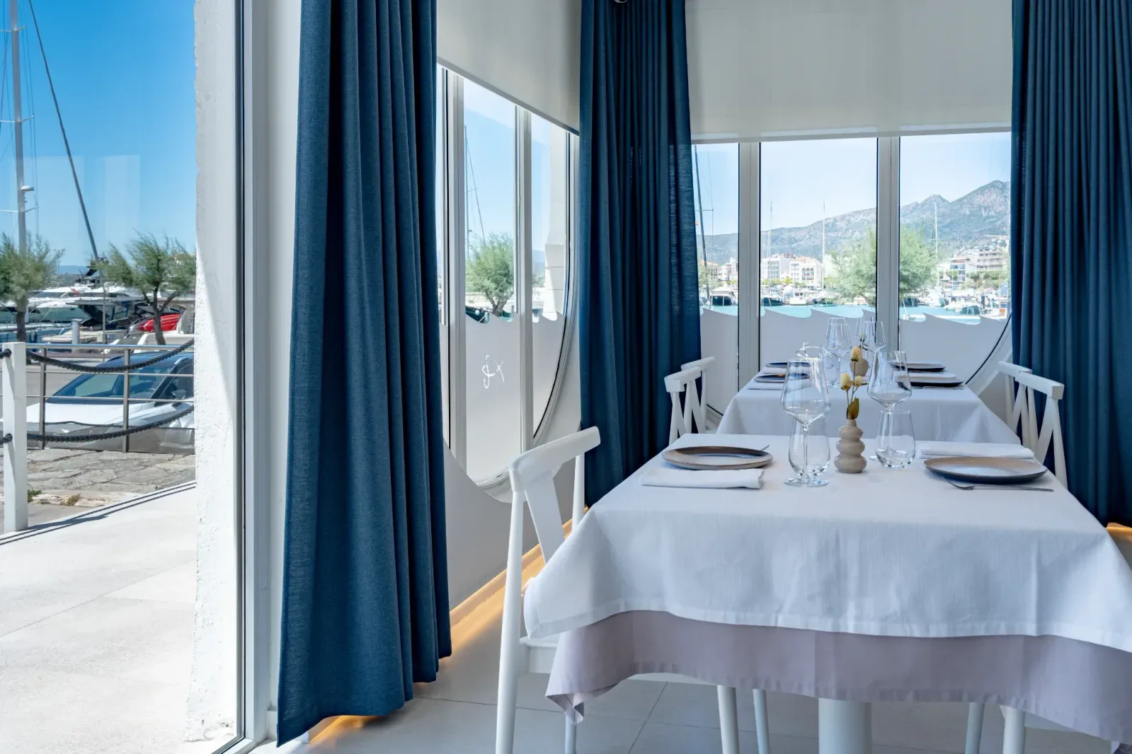 Comedor luminoso en Restaurant La Llotja en la costa mediterránea de España, con mesa vestida y vistas al puerto deportivo