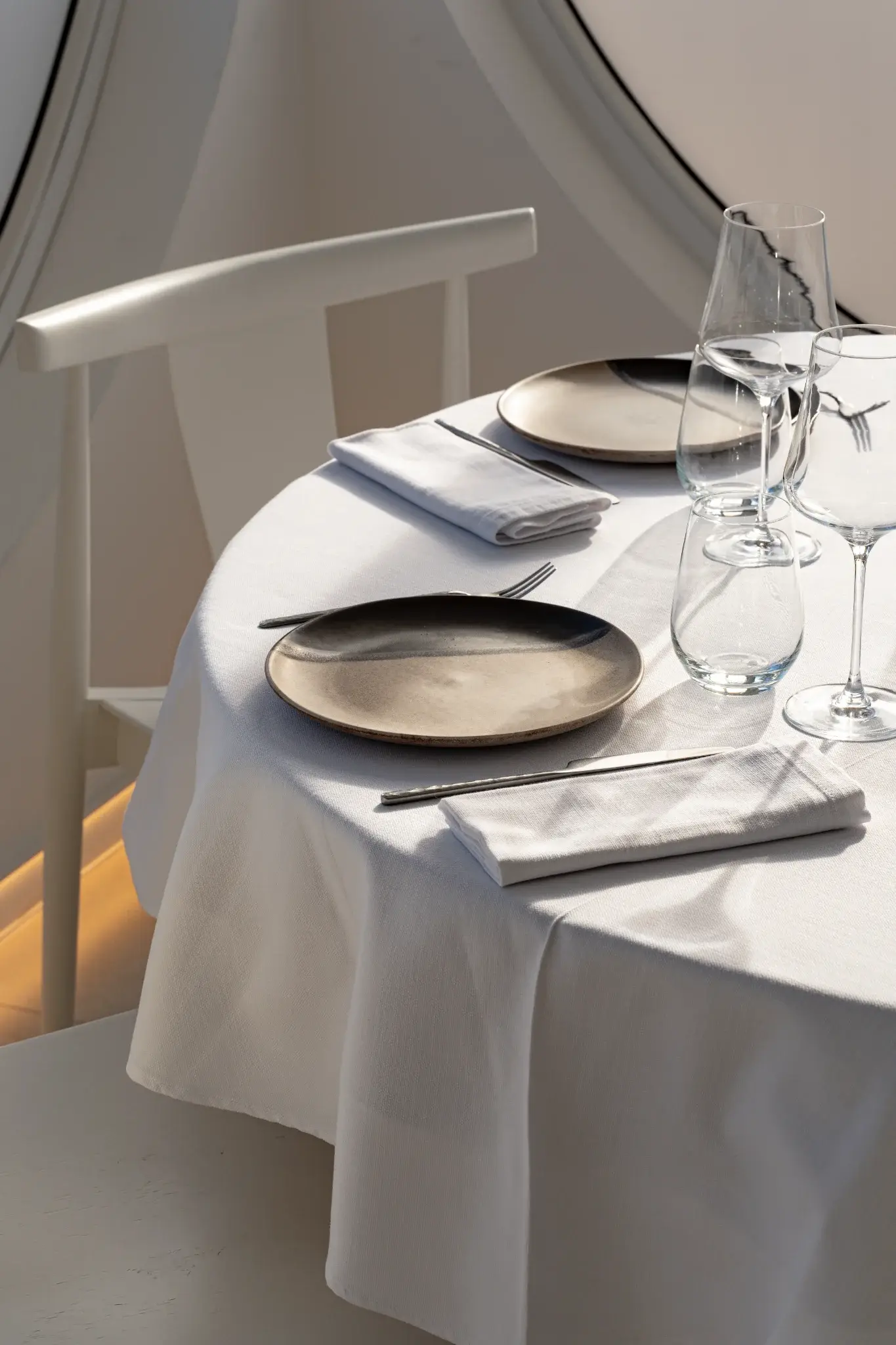 Mesa redonda elegantemente preparada con vajilla minimalista y copas en Restaurant La Llotja, comedor luminoso en Spain, cocina mediterránea